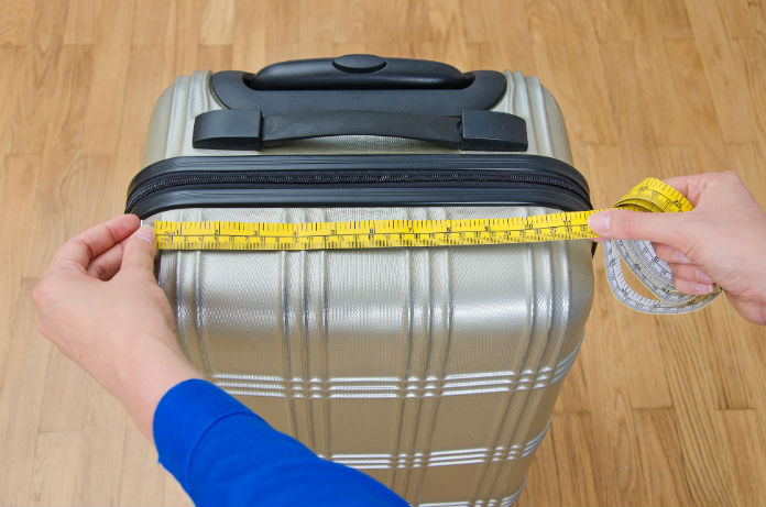 person examining suitcase with a measuring tape