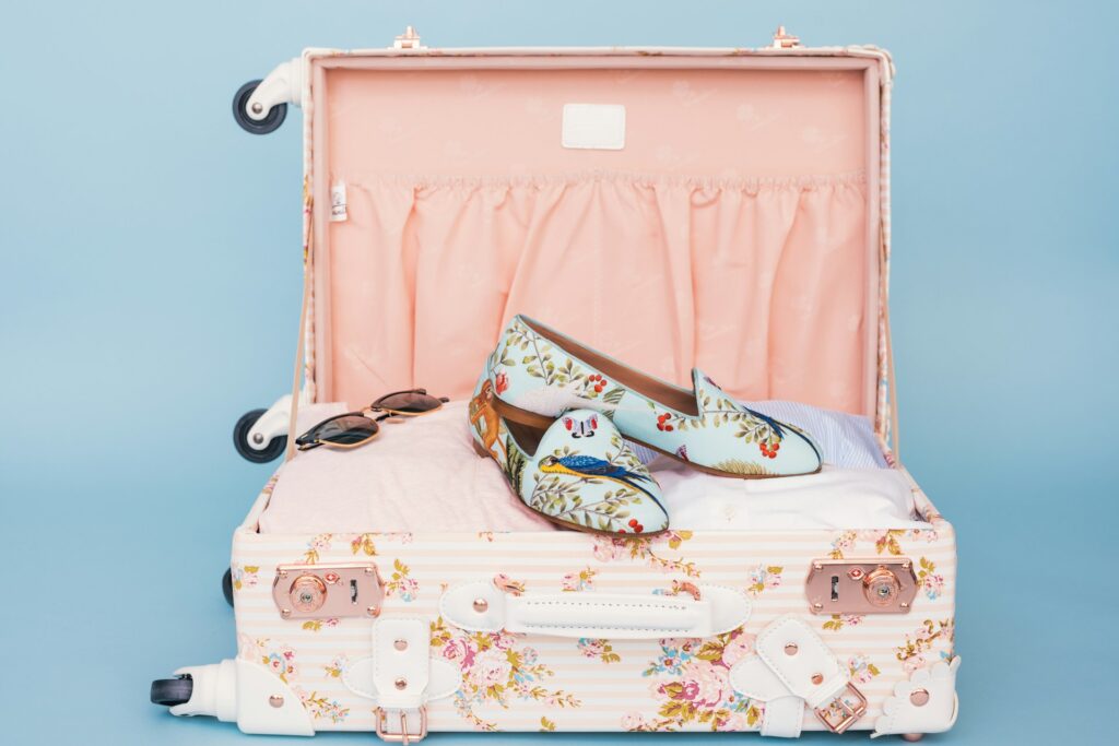 A light coloured suitcase packed with clothes and shoes