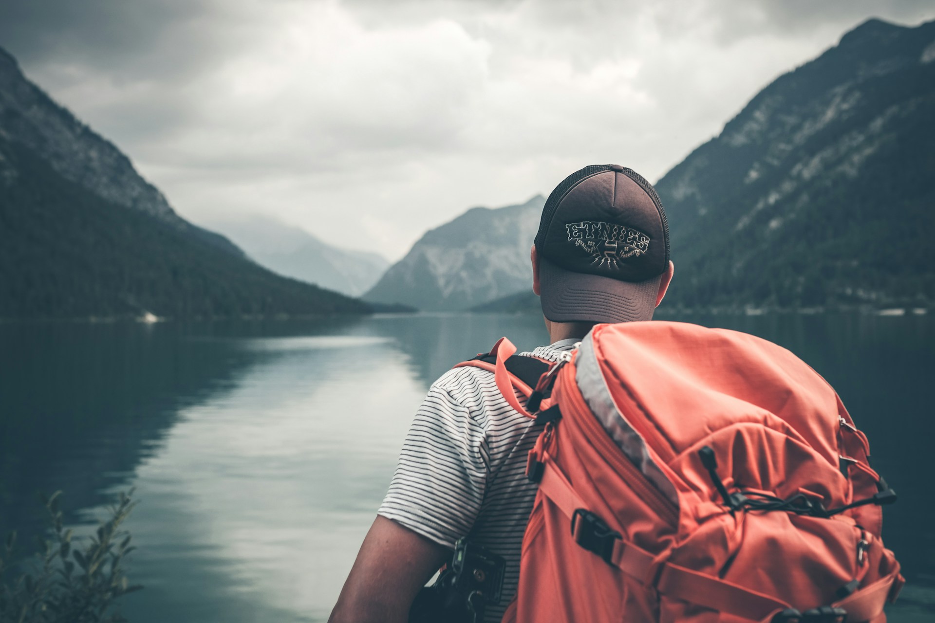 A man with a large rucksack looking over a lake