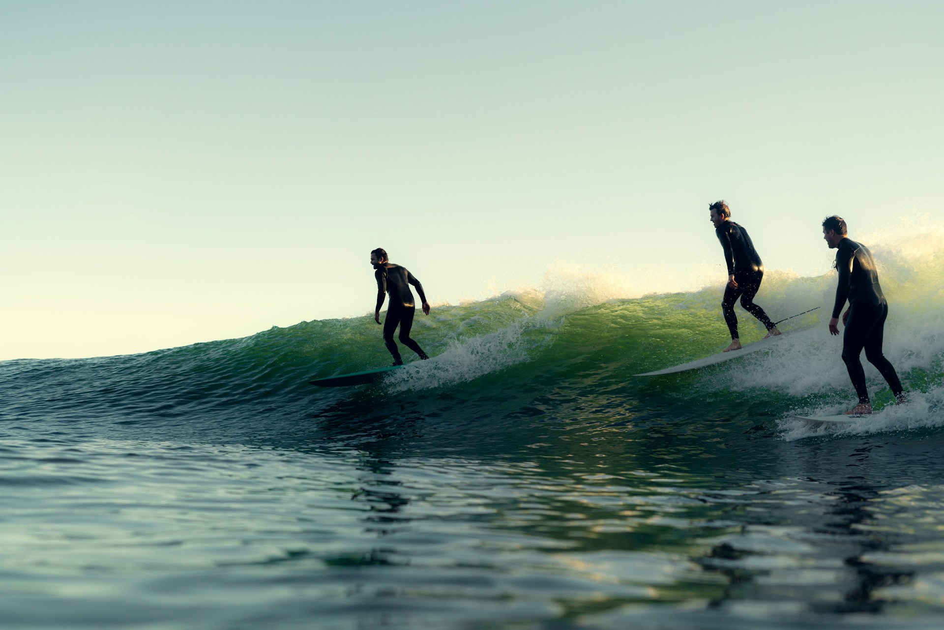 Three surfers riding a wave