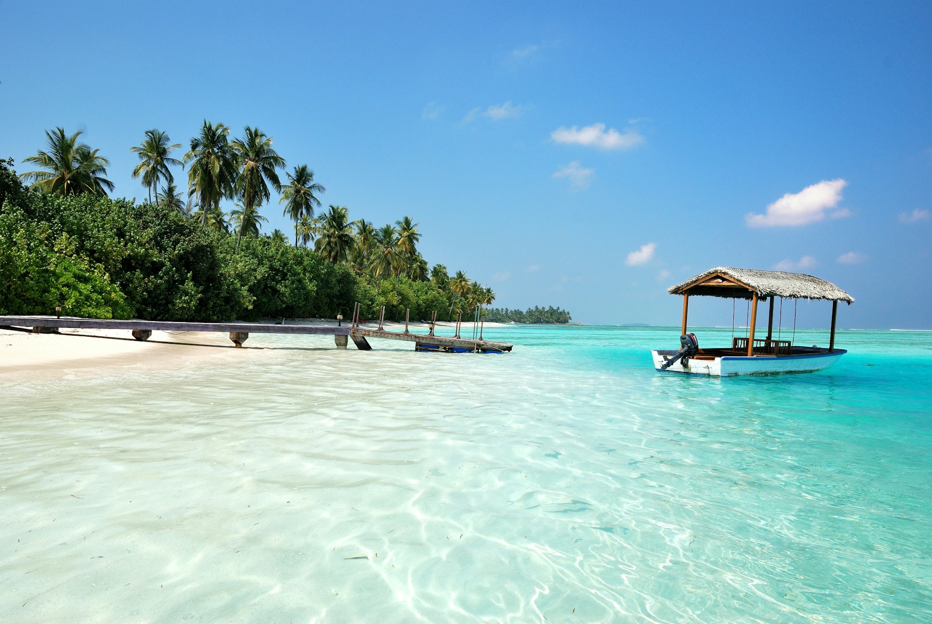 A quiet beach with a small boat and clear waters in the Maldives