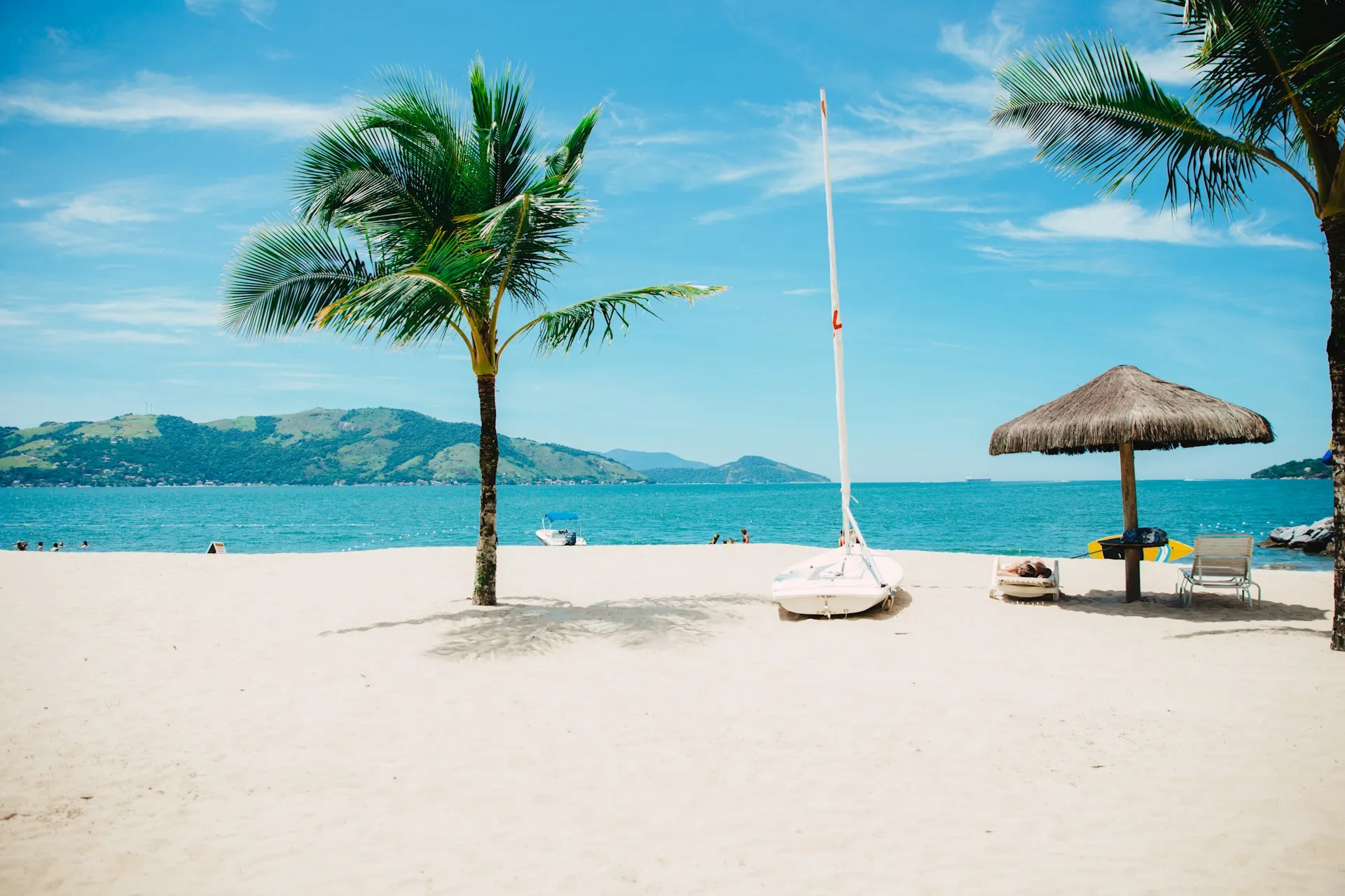 A beach with palm trees, chairs and a parasol