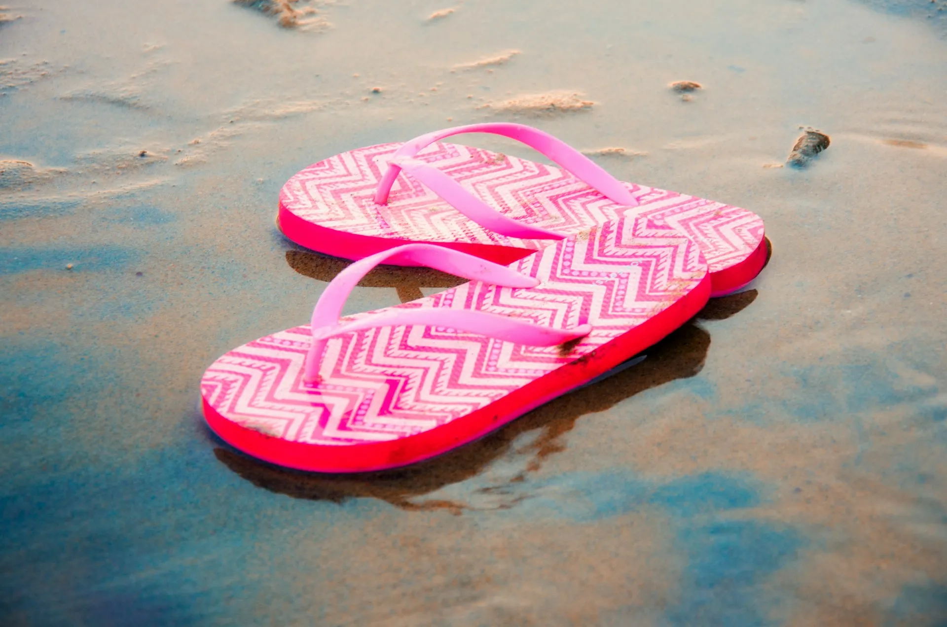 A pair of flip flops on wet sand