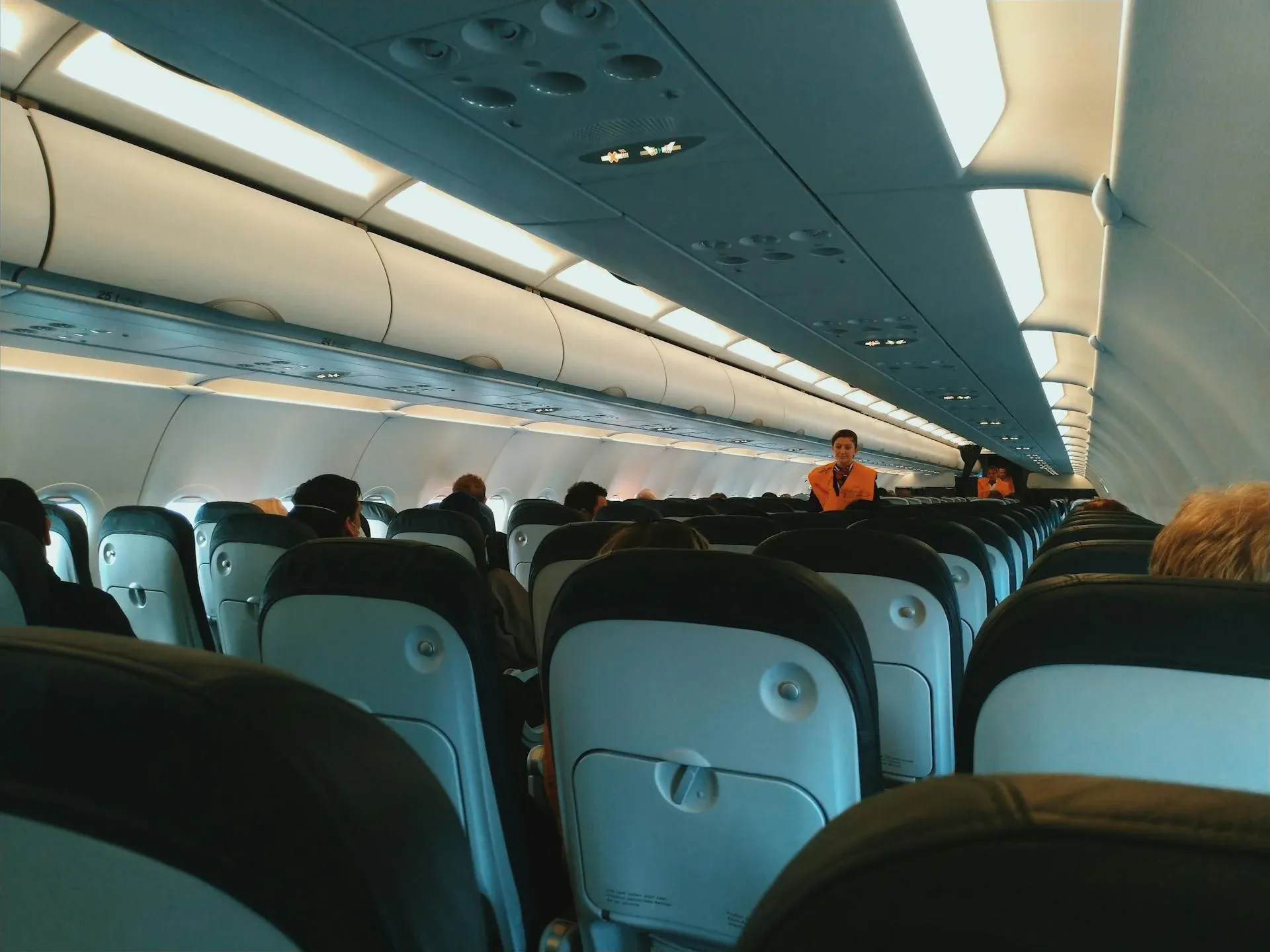 Rows of seats on a plane, with an attendant in the aisle