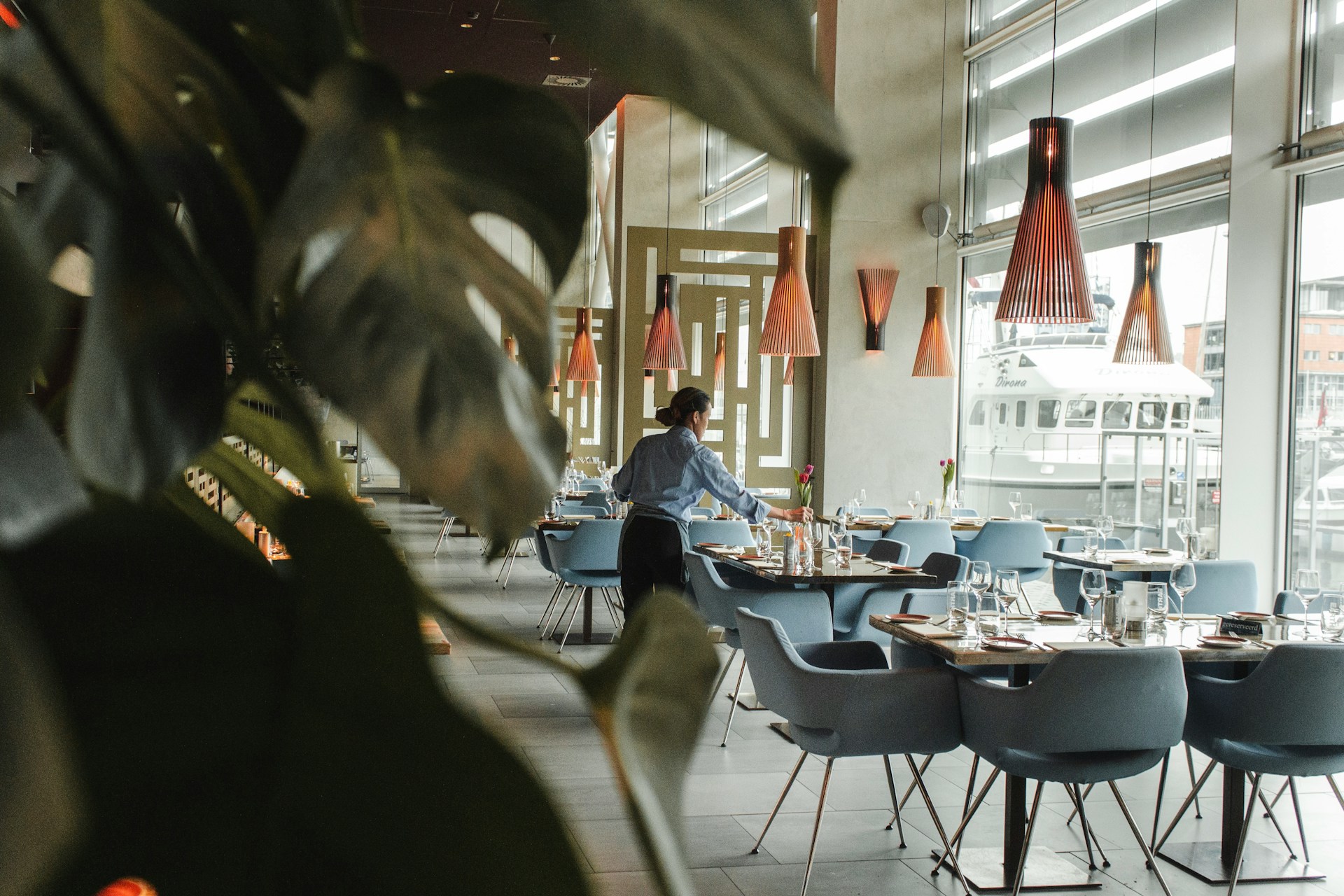 An empty restaurant with a waitress setting tables
