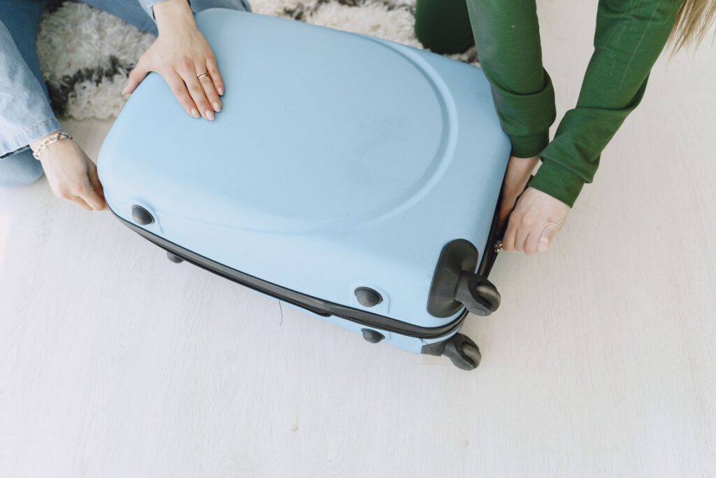 Two people handling a bright blue suitcase